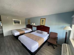een hotelkamer met 2 bedden en een stoel bij Rodeway Inn in Lake Wales