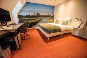 - une chambre avec un grand lit et un bureau dans l'établissement De Eenhoorn, à Oostbourg