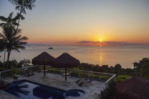 einen Sonnenuntergang über dem Meer mit Pool in der Unterkunft Pousada Recanto de Paraty in Paraty