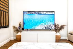 a living room with a flat screen tv on a white cabinet at Iconic PRIVE beachfront villa Mola Kaliva in Mola Kalyva