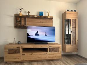 a living room with a television on a wooden entertainment center at Ferienwohnung TAUNUSIDYLLE 