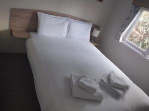 a large white bed with two towels on it at Tree tops - 2 bedroom static caravan with decking in Hastings