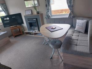 a living room with a couch and a table and a tv at Tree tops - 2 bedroom static caravan with decking in Hastings