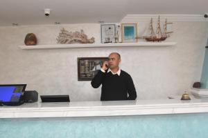 a man standing at a counter talking on a cell phone at Hotel L'Initiale in Oualidia