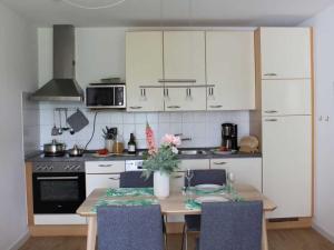 a kitchen with a table with chairs and a kitchen with white cabinets at Residenz Haffblick Wohnung 31 in Boltenhagen