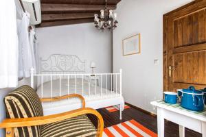 - un lit bébé dans une chambre avec une chaise et une table dans l'établissement Original stone house with patio in the city center, à Alaçatı