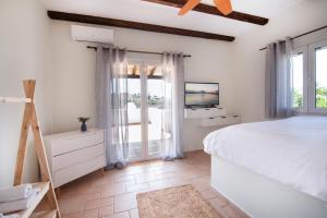 a white bedroom with a bed and a tv at Villa Xenia in Áyioi Asómatoi