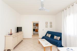 a living room with a blue couch and a tv at Villetta Aurora in San Teodoro