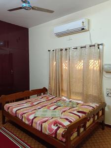 a bedroom with a bed with a curtain and a window at Maria Vilas in Tirunelveli