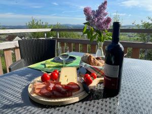 a bottle of wine and a plate of food on a table at Wohlfühl-Haus mit Panoramablick in Oberneuforn