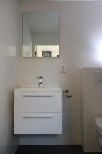a white bathroom with a sink and a mirror at Studio Eb in Egmond aan Zee +14 photos