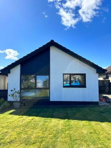 a white house with large windows on a yard at Sleeps7-Parking-Garden-Patio in Johnstone