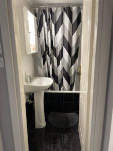 a bathroom with a sink and a black and white shower curtain at Διαμέρισμα με θέα σε πάρκο! in Serres