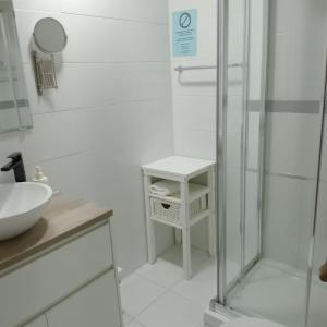 a white bathroom with a shower and a sink at Alojamientos el Paramo in San Vicente de la Barquera