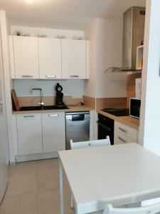 a kitchen with white cabinets and a white table at Domaine de la lumière in Saint-Jean-de-Monts