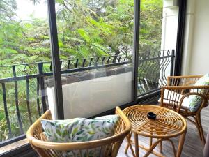balcón con 2 sillas, mesa y ventana en Residence Le Point Choisy en Pointe aux Cannoniers