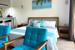 een slaapkamer met een bed en twee blauwe stoelen bij Residence Le Point Choisy in Pointe aux Cannoniers