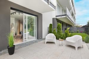a patio with two white chairs and a table at 5 minut do Plaży - Apartament MORZETU z Tarasem by Renters in Gąski