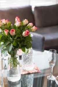 a vase filled with pink roses sitting on a table at 5 minut do Plaży - Apartament MORZETU z Tarasem by Renters in Gąski