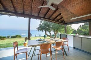 a dining room with a table and chairs and the ocean at Iconic PRIVE beachfront villa Mola Kaliva in Mola Kalyva