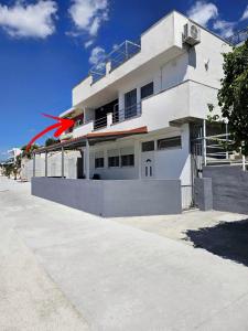 Ein weißes Haus mit einem roten Pfeil drauf. in der Unterkunft Apartment Hajdi in Podstrana