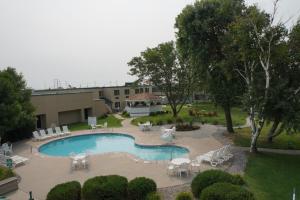 una piscina con sillas y mesas y un edificio en The Biltmore Hotel & Suites Main Avenue, en Fargo