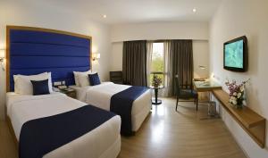 een hotelkamer met 2 bedden en een bureau bij Peerless Hotel Hyderabad in Hyderabad