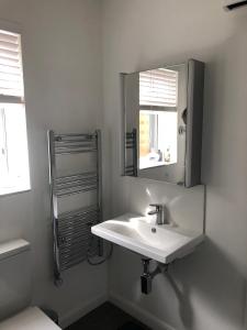 a white bathroom with a sink and a mirror at Spacious self-contained flat - 33AS1 in London