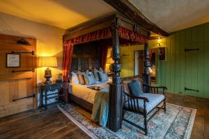 a bedroom with a bed with a fireplace and a chair at The George Inn & Plaine in Norton Saint Philip