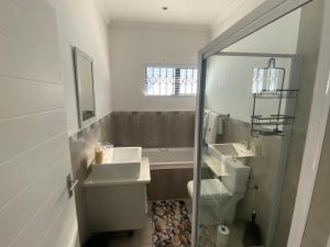 a white bathroom with two sinks and a shower at 32 On Gill Road Self Catering in Cape Town +18 photos