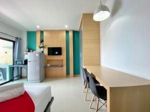 a room with a bed and a desk and a kitchen at Phoomjai Service Apartment in Ban Klang