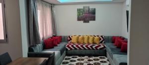 a living room with a couch with red and yellow pillows at Adan Beach appartment in front of Atlantic in Aourir