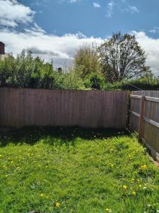 einen Hinterhof mit einem Holzzaun und einem grünen Garten in der Unterkunft Contemporary 3 bedroom house in Nottingham