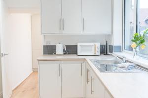 a white kitchen with a sink and a microwave at 24 Baden Powell in Barrow in Furness