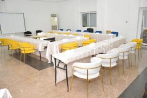 Freedom Palace Hôtel في بورتو-نوفو: قاعة اجتماعات بمناضد بيضاء وكراسي صفراء