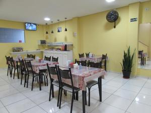 a dining room with tables and chairs and a kitchen at Hotel Biz a 8 minutos do Brás, a 15 minutos da 25 de março e a 8 minutos do Bom retiro in Sao Paulo