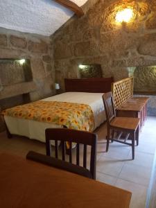een slaapkamer met een bed en een tafel en stoelen bij Horizontes Serranos in Tondela