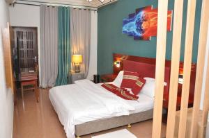 una camera da letto con un letto con lenzuola bianche e cuscini rossi di Freedom Palace Hôtel a Porto-Novo