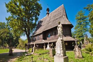 a large wooden house with a statue in front of it at Dom Pod Orzechem in Łapczyca