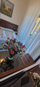 eine Vase mit Blumen auf einem Tisch neben einem Bett in der Unterkunft Hotel Dora in Levanto