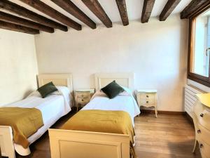 two beds in a room with white walls and wooden floors at Lo Squero apt in Venice