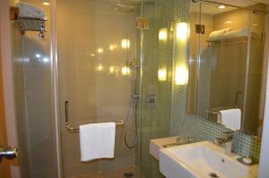een badkamer met een douche, een wastafel en een spiegel bij Peerless Hotel Hyderabad in Hyderabad