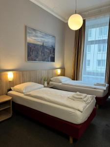 Hotel Kieler Hof am Hauptbahnhof - Hamburg Central Station في هامبورغ: سريرين في غرفة الفندق مع نافذة كبيرة