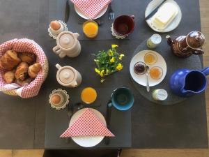 uma mesa com alimentos de pequeno-almoço e chávenas de sumo de laranja em Le Spa est dans le Pré em Triguères