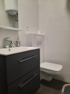 a white bathroom with a sink and a toilet at Apartman Smokva in Vodice