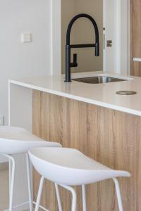 a kitchen with a sink and two white chairs at Luxury Villa Pilar De La Horadada in Pilar de la Horadada