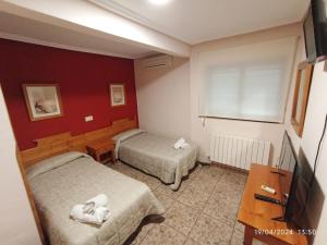 una camera d'albergo con due letti e una televisione di HOTEL GRAN VIA a Calera y Chozas