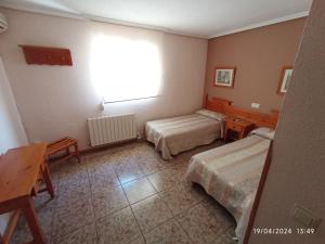 Cette chambre comprend 2 lits, une table et une fenêtre. dans l'établissement HOTEL GRAN VIA, à Calera y Chozas