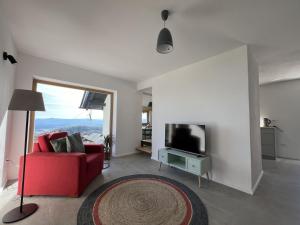 sala de estar con sofá rojo y TV en Elipa Cottage en Cerklje na Gorenjskem