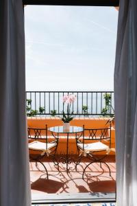 uma varanda com uma mesa com um vaso de flores em Villa Principe Giovanni em Positano